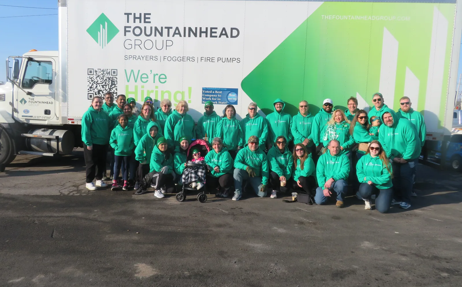 Fountainhead Group employees in matching green hoodies gathered in front of an FGI delivery truck